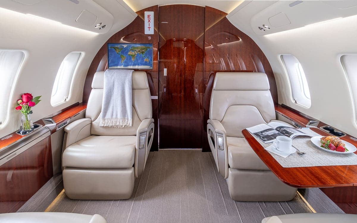 Challenger interior with leather seats and a table with a magazine and food.