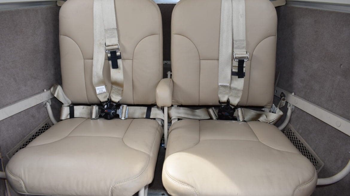 Close-up of two tan leather seats with seatbelts in the King Air cabin.