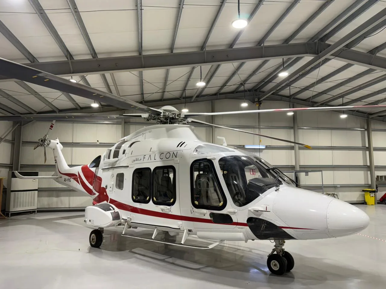Angle view of the A6-FHG helicopter parked inside a hangar.