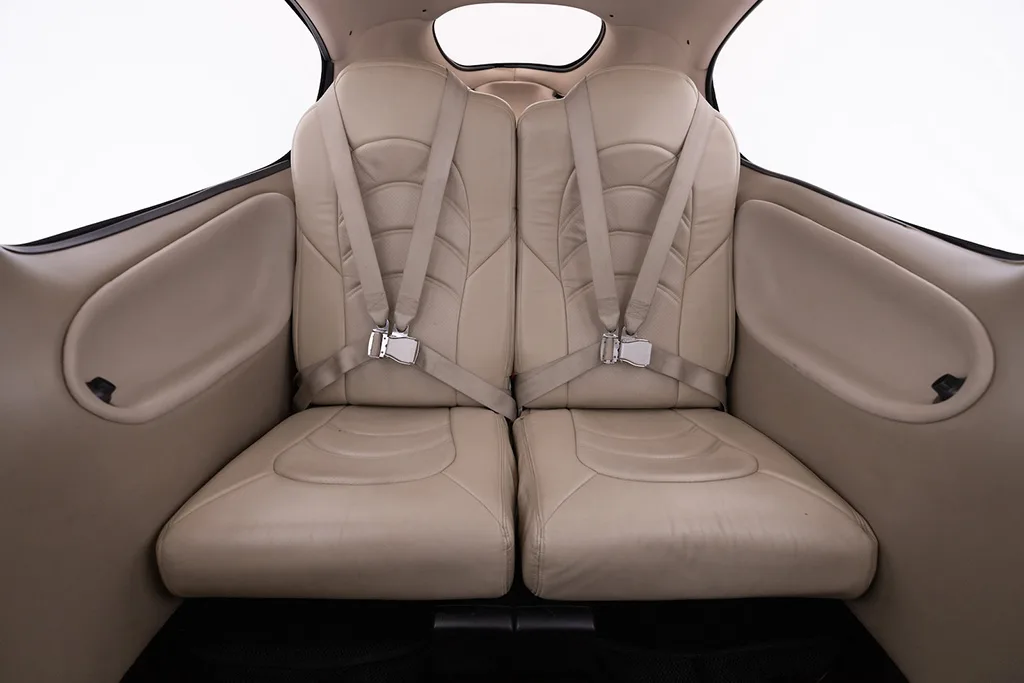 The beige leather rear seats of a Cirrus SR22 aircraft cabin with seatbelts fastened.