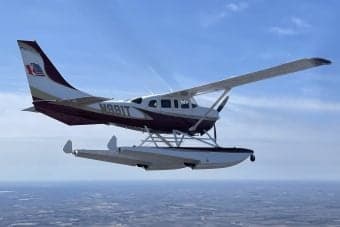 Float plane N991T in flight over a landscape.