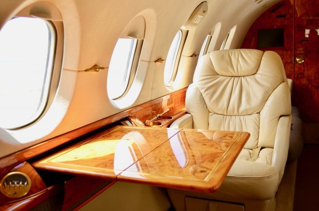 Interior of the aircraft with a leather seat and wooden table.