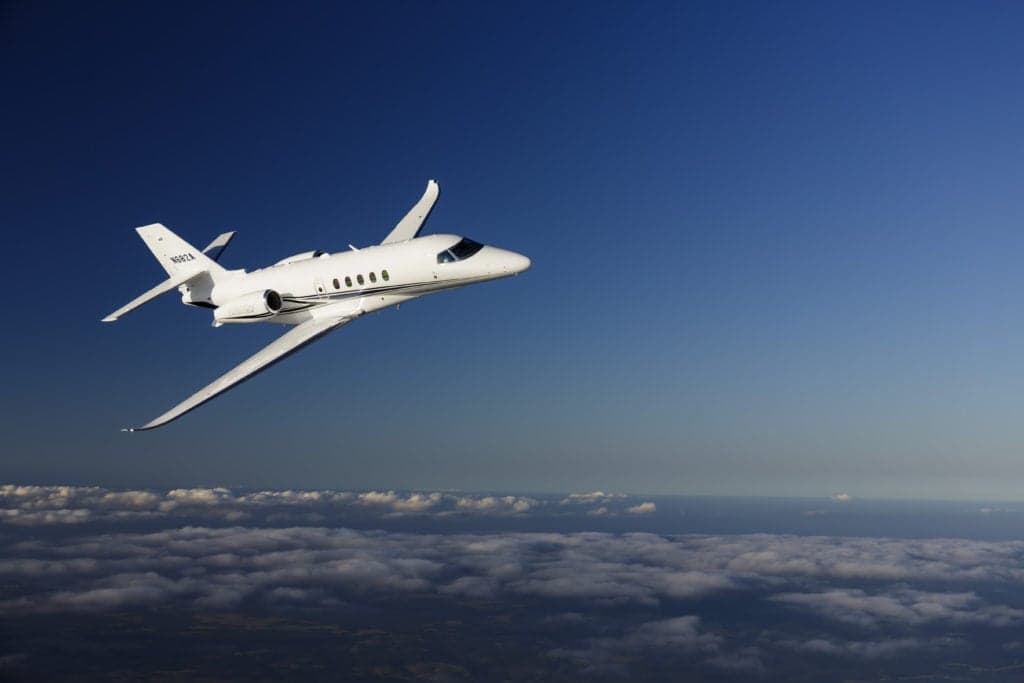 A Citation Latitude jet in flight over clouds.