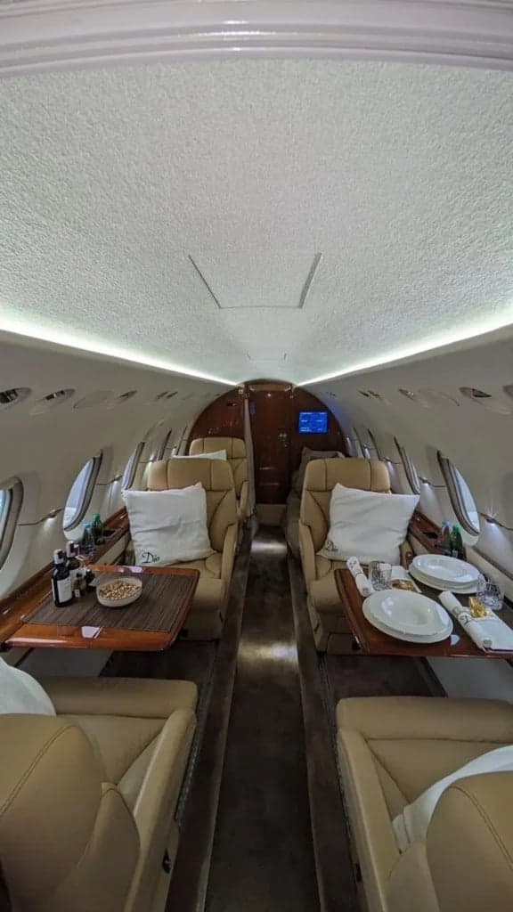 A view of the aircraft's interior with tan leather seats and wooden tables.