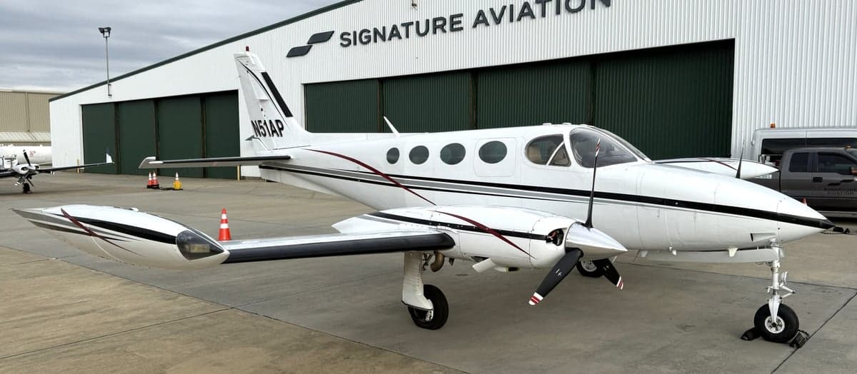 A white and black Cessna 340A aircraft with registration N51AP parked in front of a Signature Aviation hangar.
