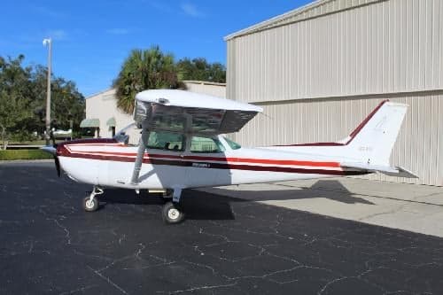 A Cessna 172 Skyhawk with a white and maroon paint scheme parked on the tarmac.
