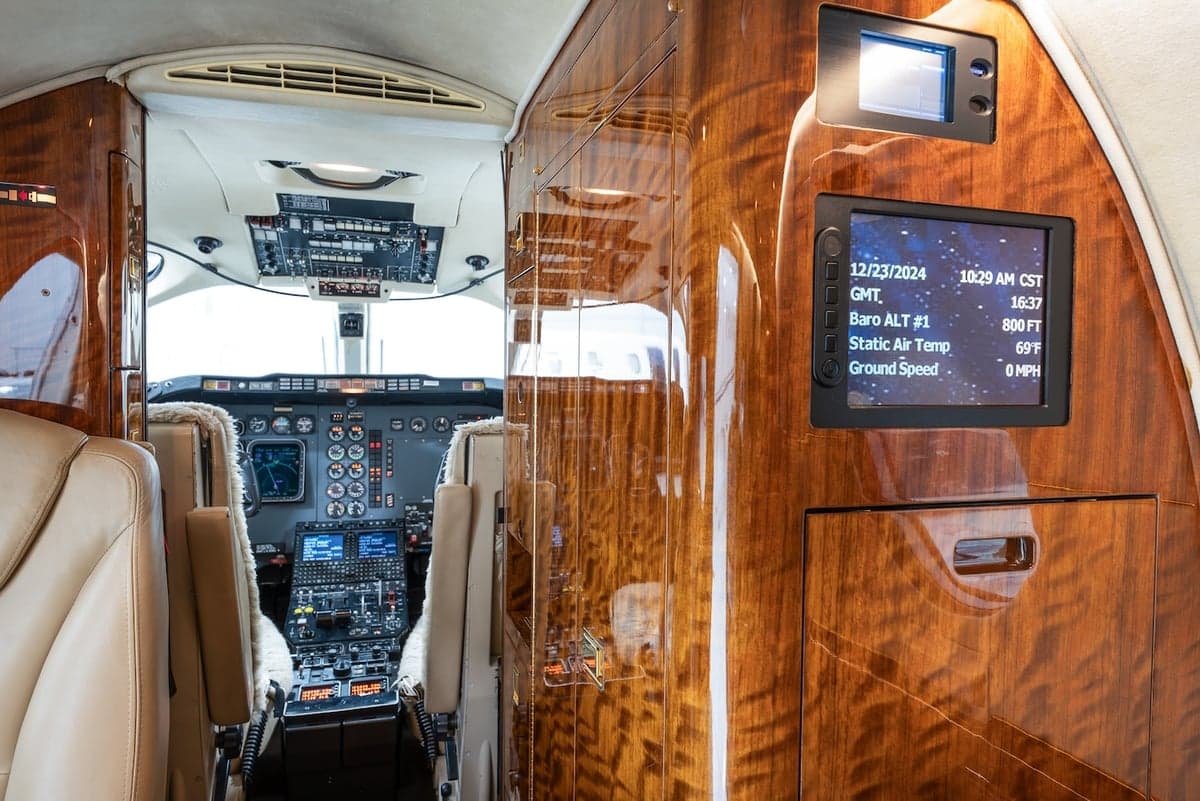 View of the cockpit from the cabin, with a display showing flight information.