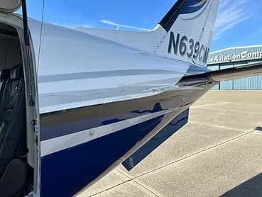 Close up of the tail of a white and blue aircraft.
