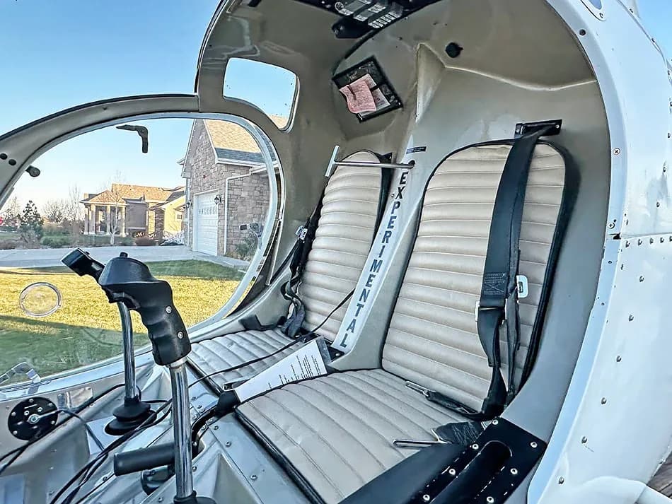 Interior view of the helicopter cockpit showing two tan seats with "EXPERIMENTAL" written on the seat belt.