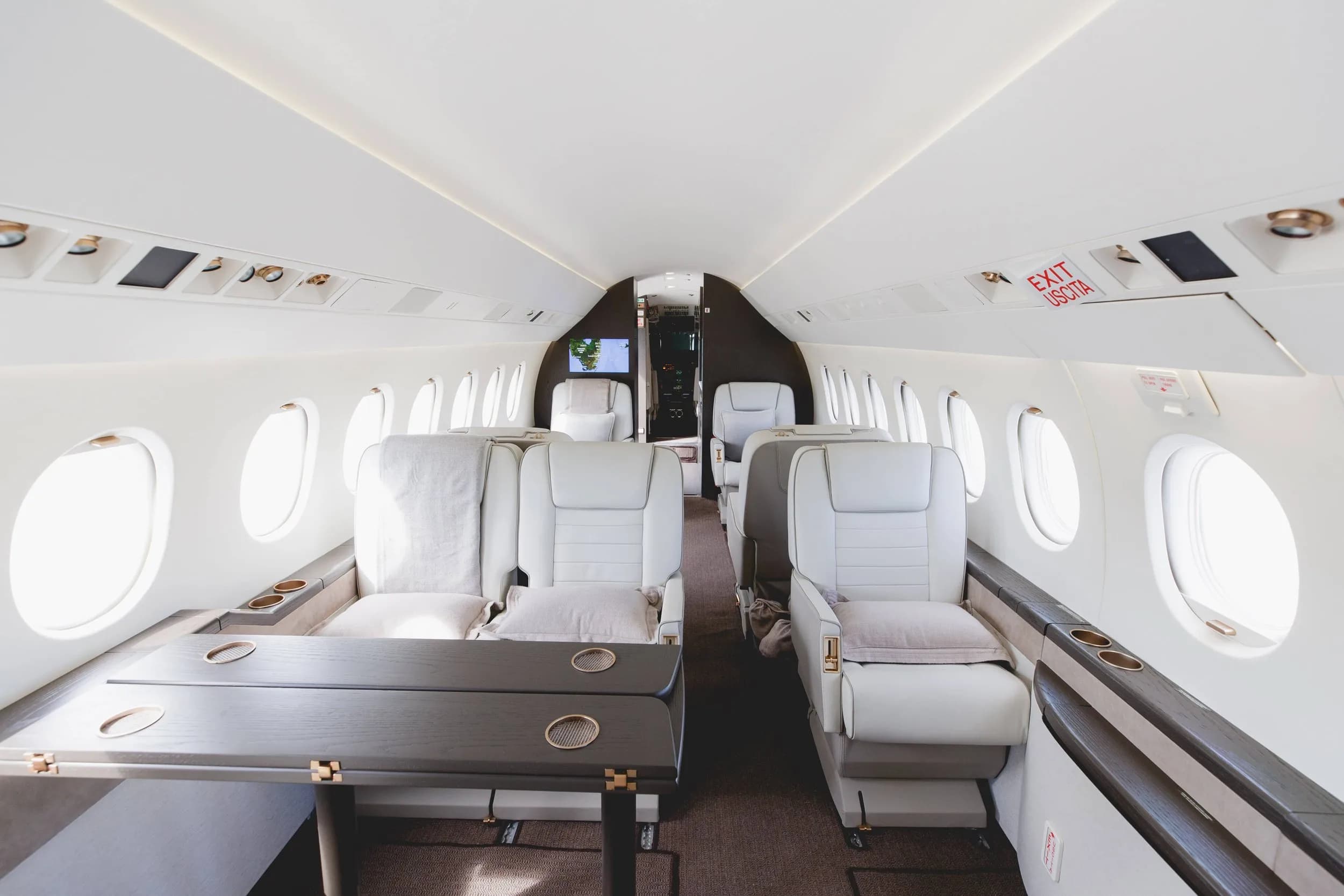 A wide view of the aircraft cabin aisle with multiple white leather seats and a table.