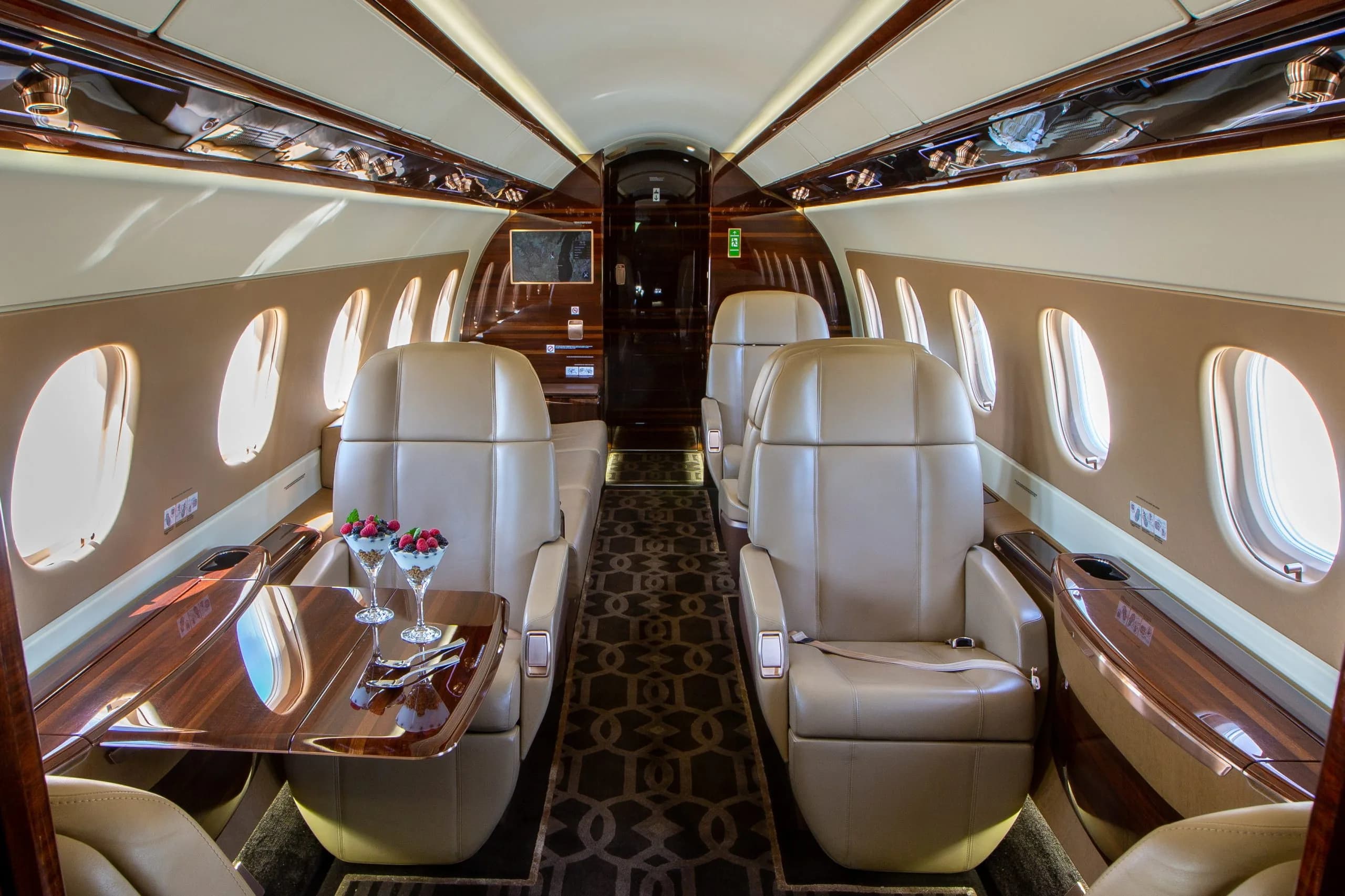 The interior of an Embraer Phenom 300E with leather seats and a table.