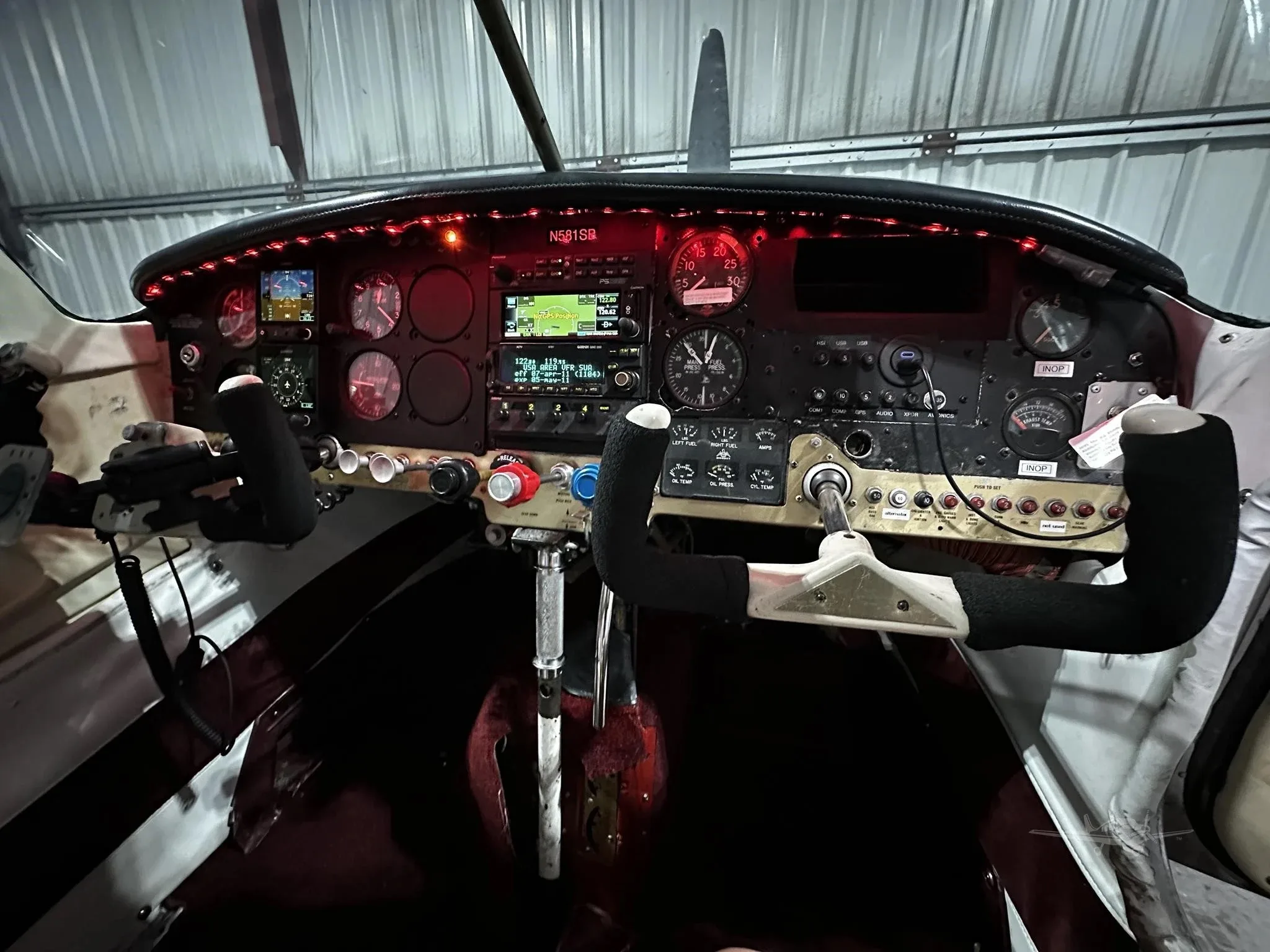 A wider view of the illuminated cockpit instrument panel of the Mooney M20 Mark 21, with control yokes visible.