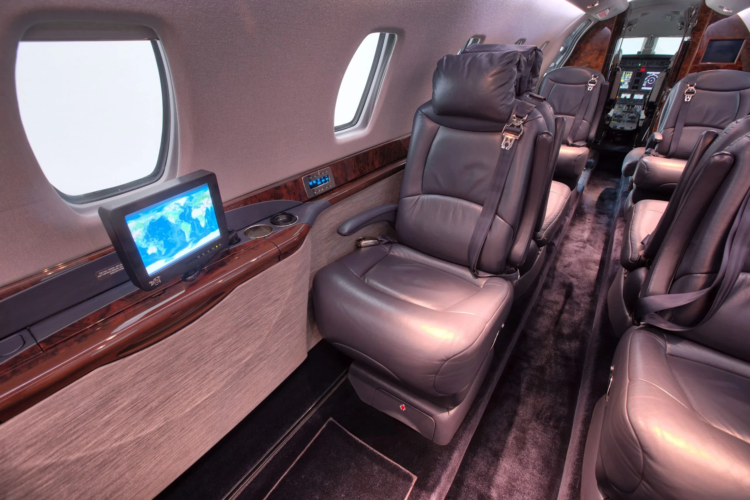 A view of the aircraft cabin with leather seats and a monitor.