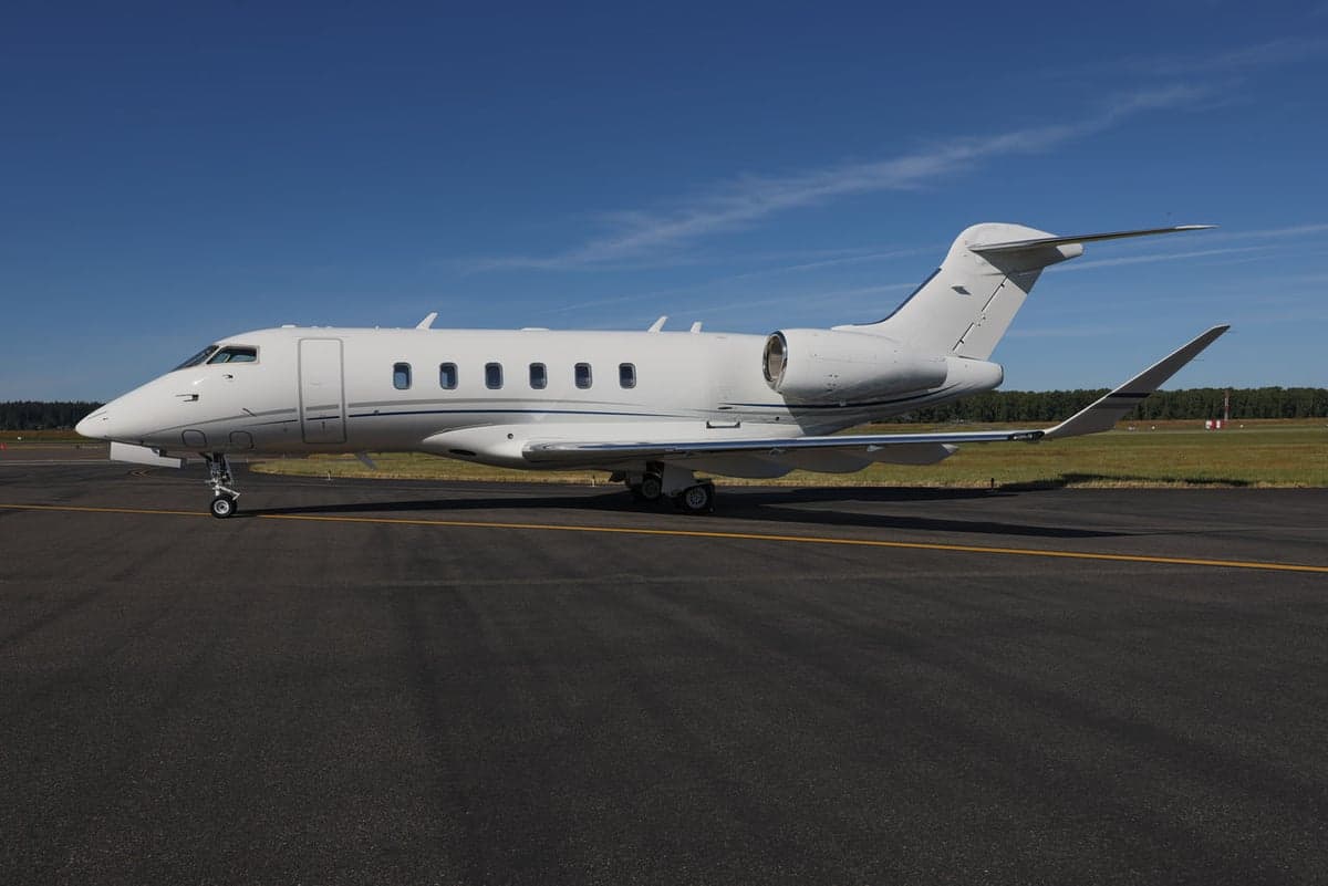 Side view of a white jet with silver accents parked on the tarmac.