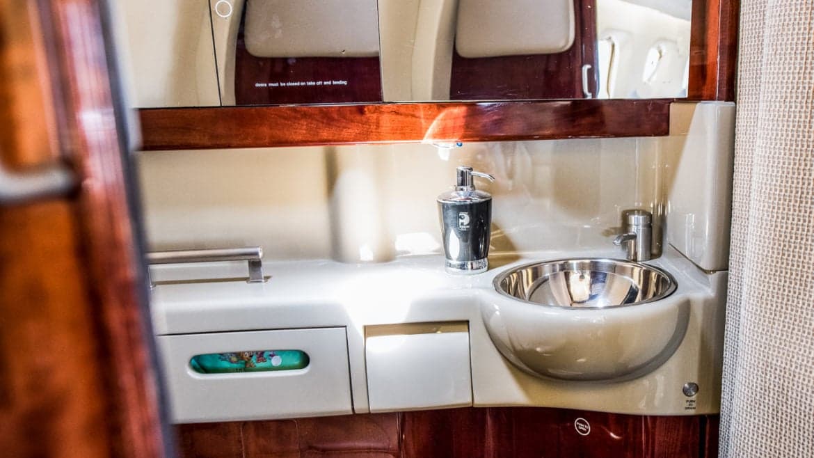 Aircraft lavatory with sink and wood trim.