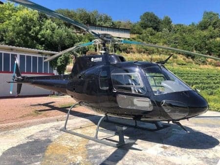 A black Airbus helicopter is parked on a helipad.