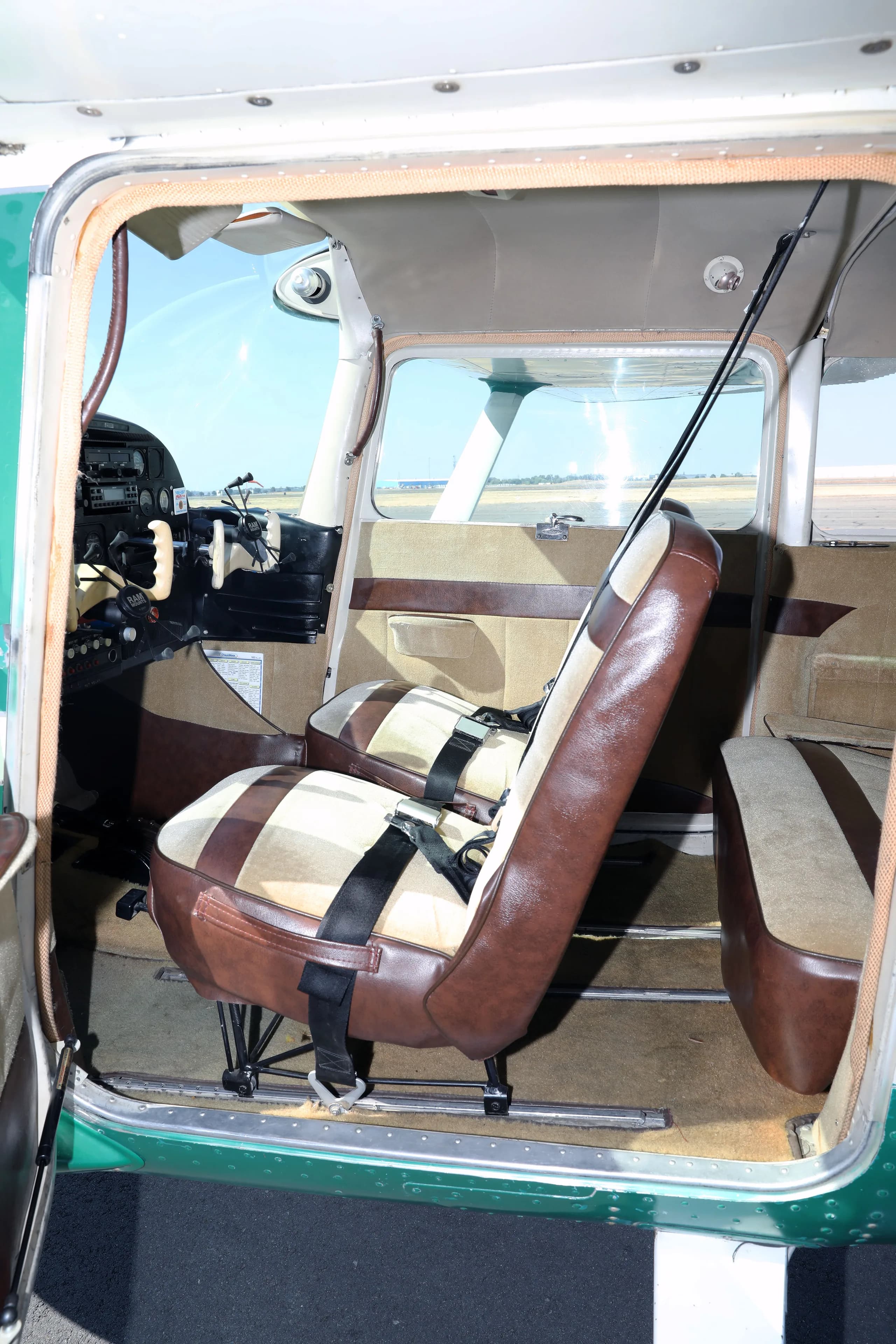The front and rear brown and tan striped cabin seats of a Cessna 182 Skylane.