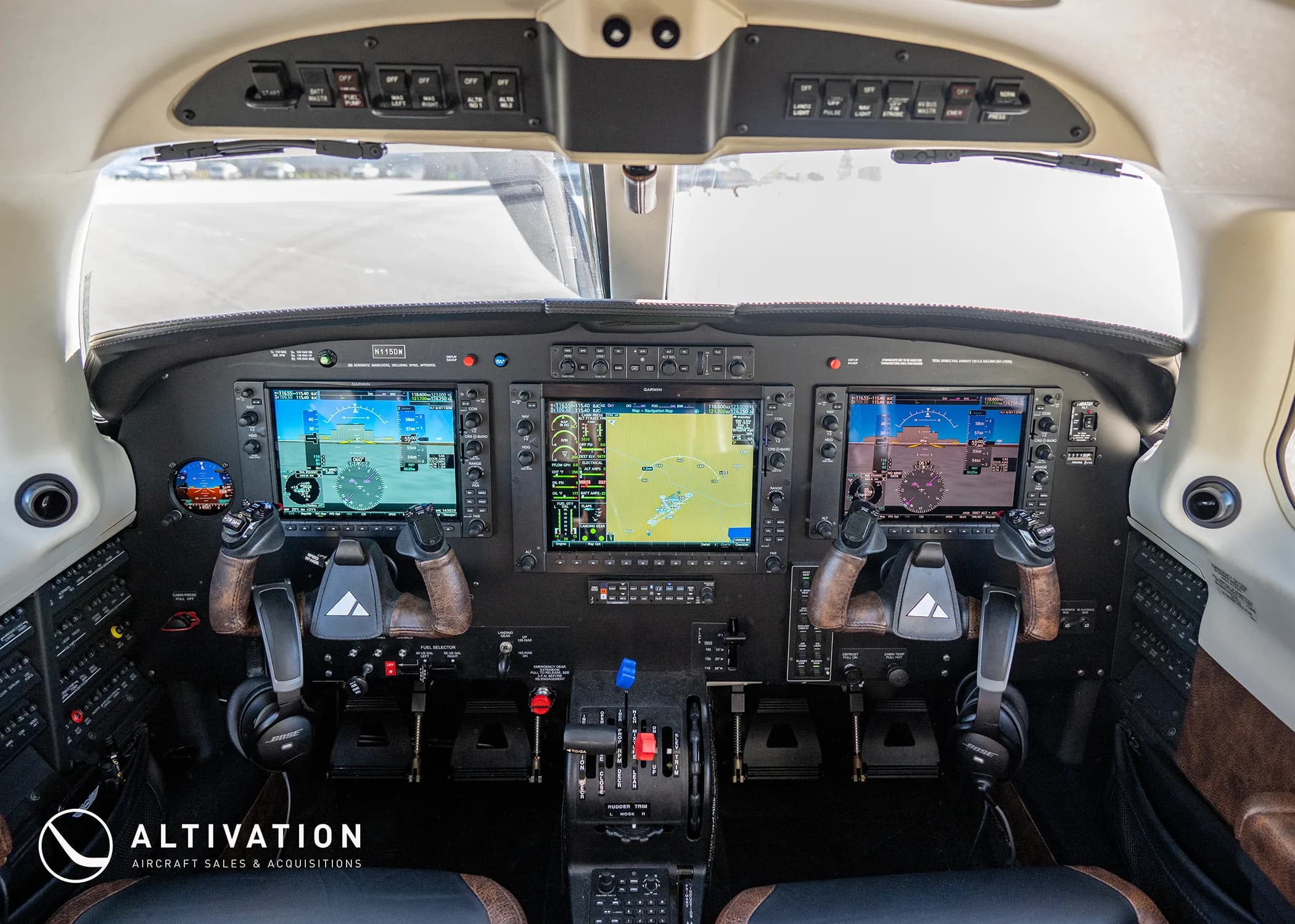 The modern glass cockpit of a Piper M350 aircraft with multiple display screens and controls, parked on an airfield.