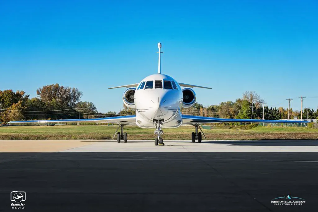 A head-on view of a white Dassault Falcon business jet with black and silver livery, registration VP-CDJ, parked on an tarmac.