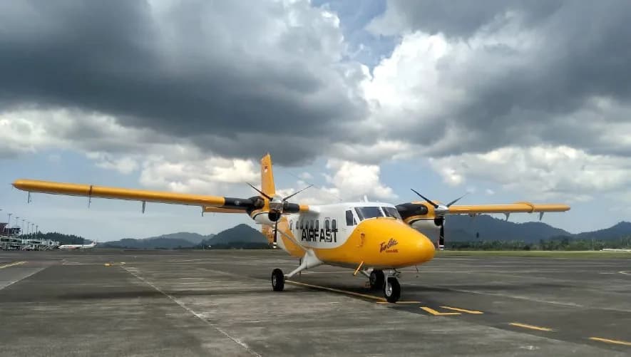 PK-OCF Twin Otter parked on the tarmac with mountains in the background.