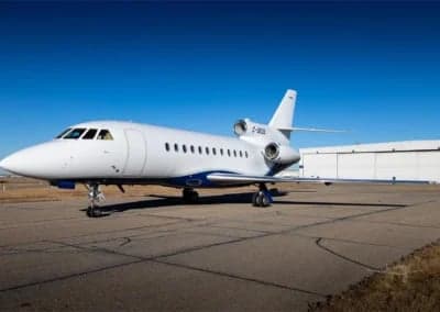 A white and blue Dassault Falcon 900EX, registration C-GEOS, parked on the tarmac.
