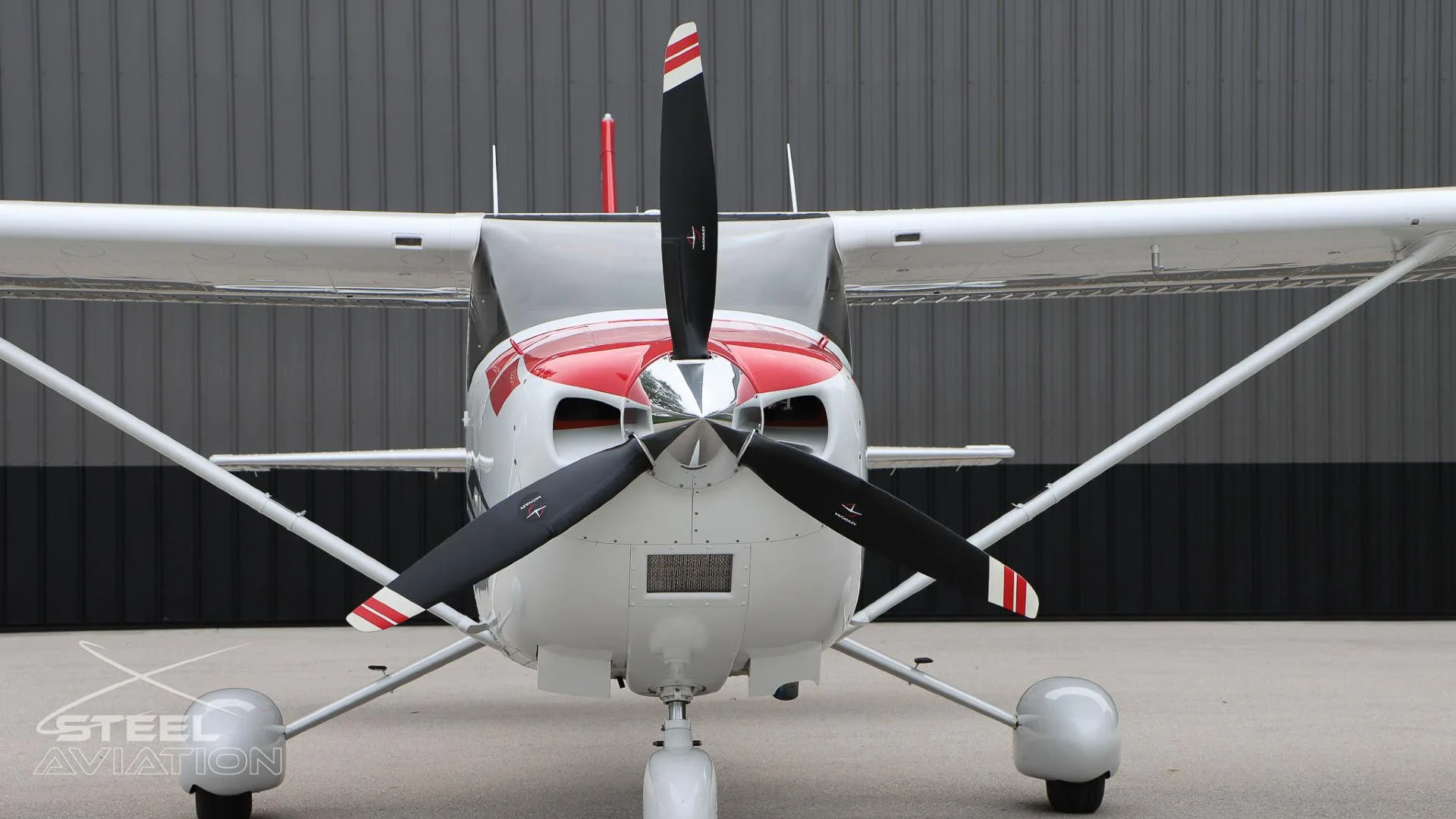 A close-up front view of the propeller and nose of a white Cessna T182T Skylane TC with red accents.