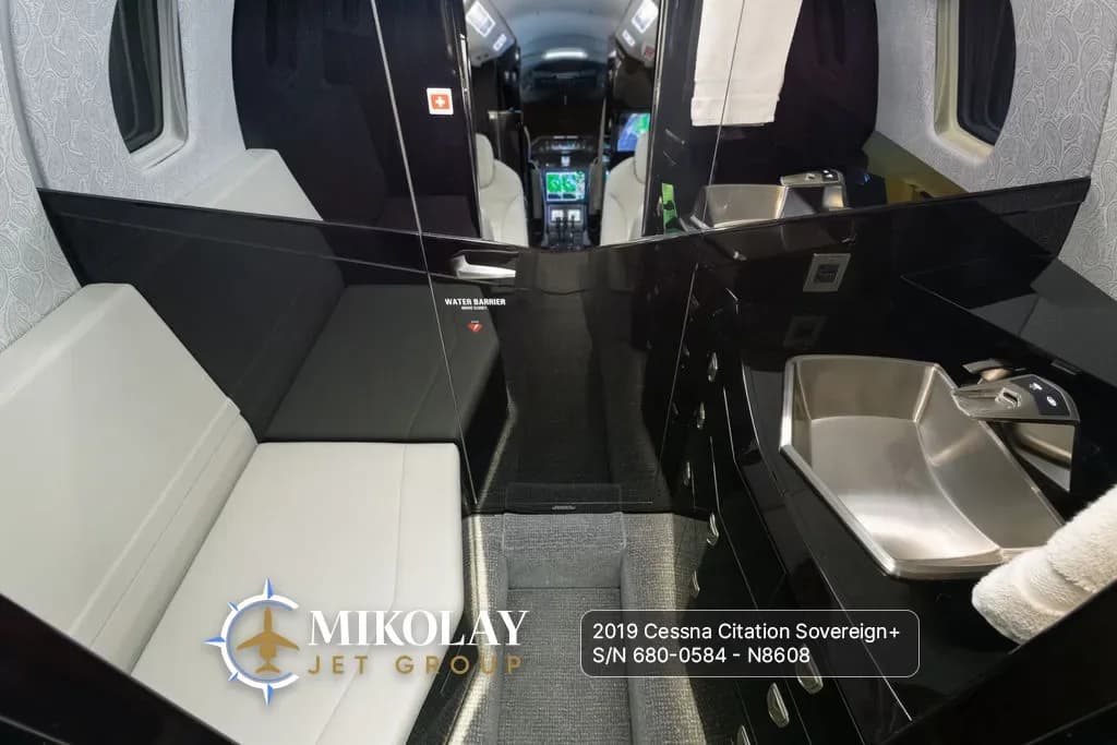 View of the aircraft galley area with dark cabinetry, a sink, and a light-colored bench seat.