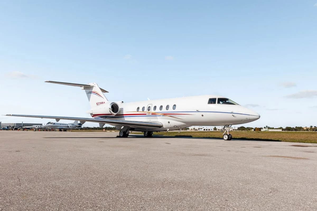 A white Hawker 800XP business jet with red and blue stripes, registration N339RA, parked on the tarmac from a front-side view.