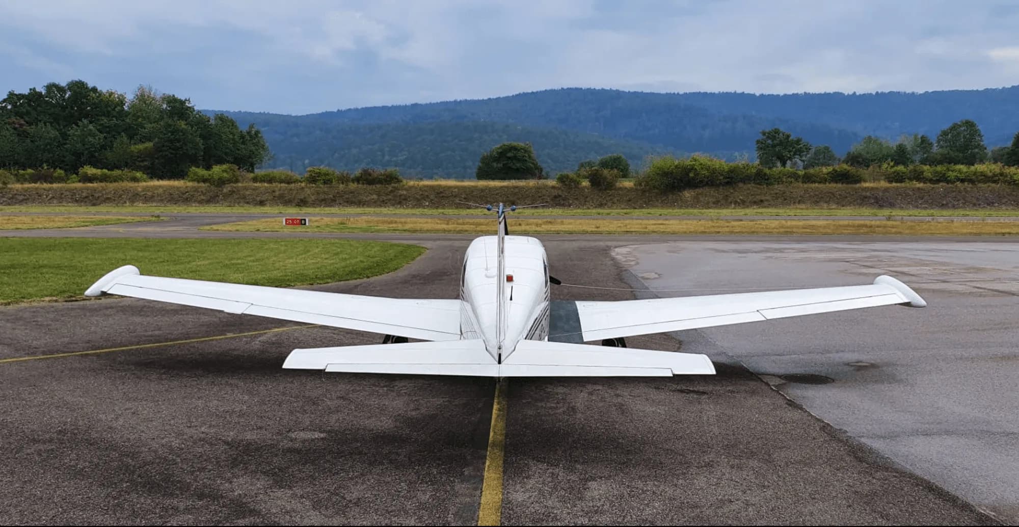 Rear view of a Piper Comanche 250 parked on a runway.