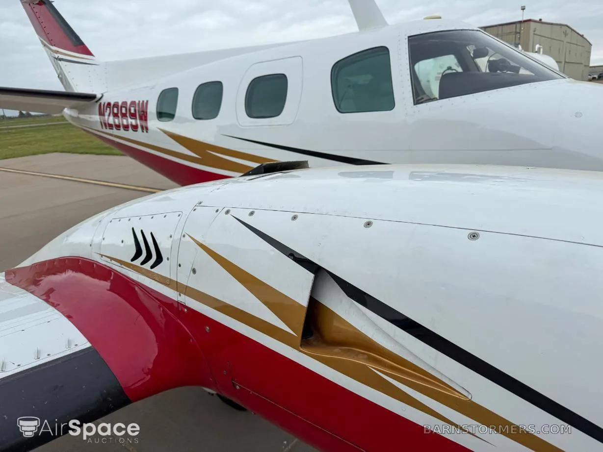 A close-up view of the white and red fuselage and engine cowling of a twin-engine aircraft with gold and black stripe accents, showing registration N2889W.