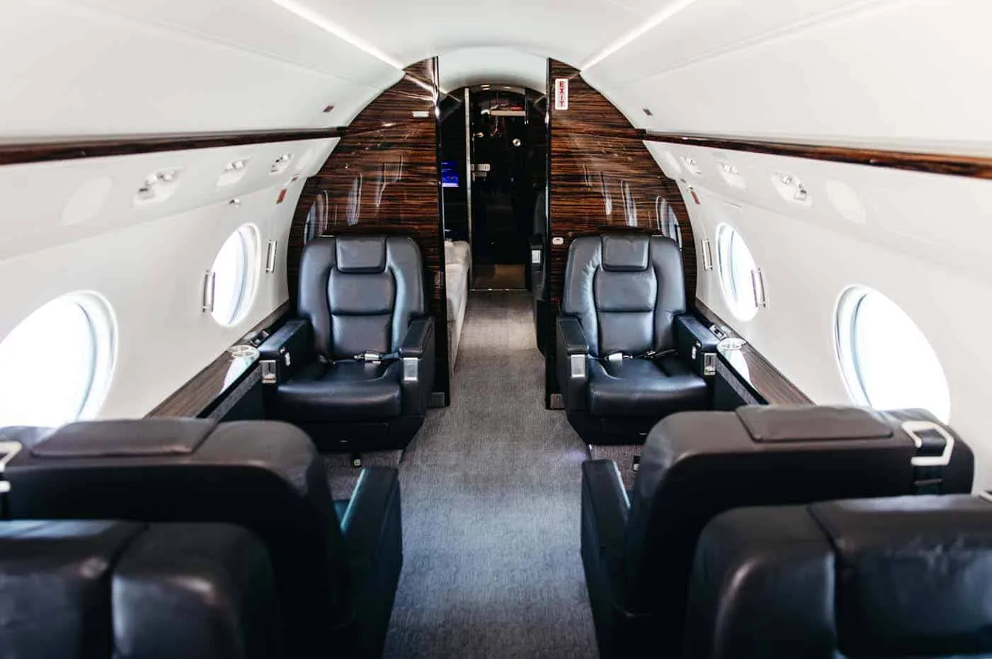A wide view of the Gulfstream G550 cabin, showcasing two sets of opposing black leather club seats.