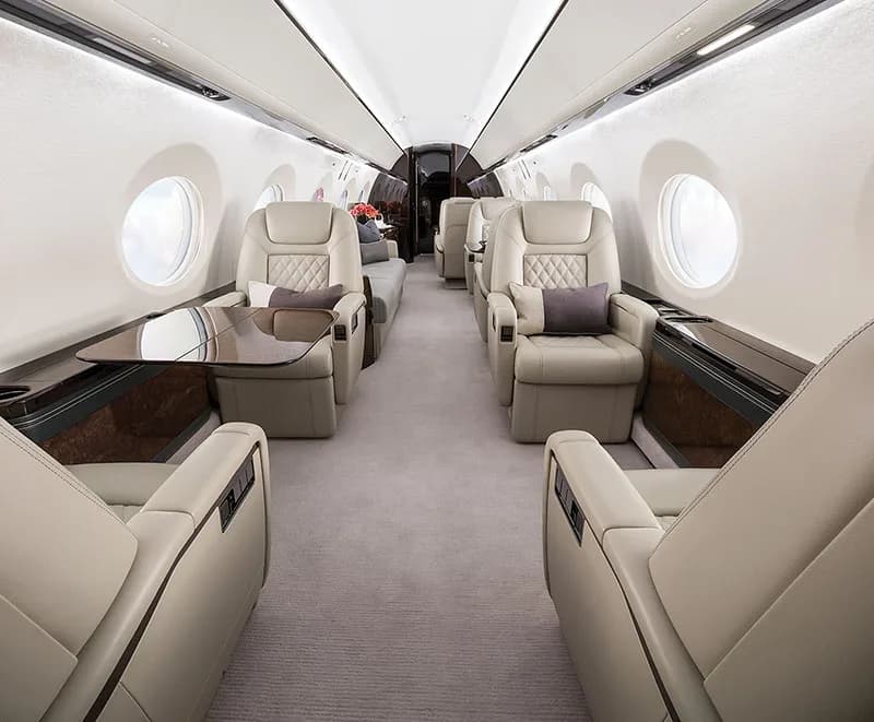 The interior of a Gulfstream jet with leather seats and a table.
