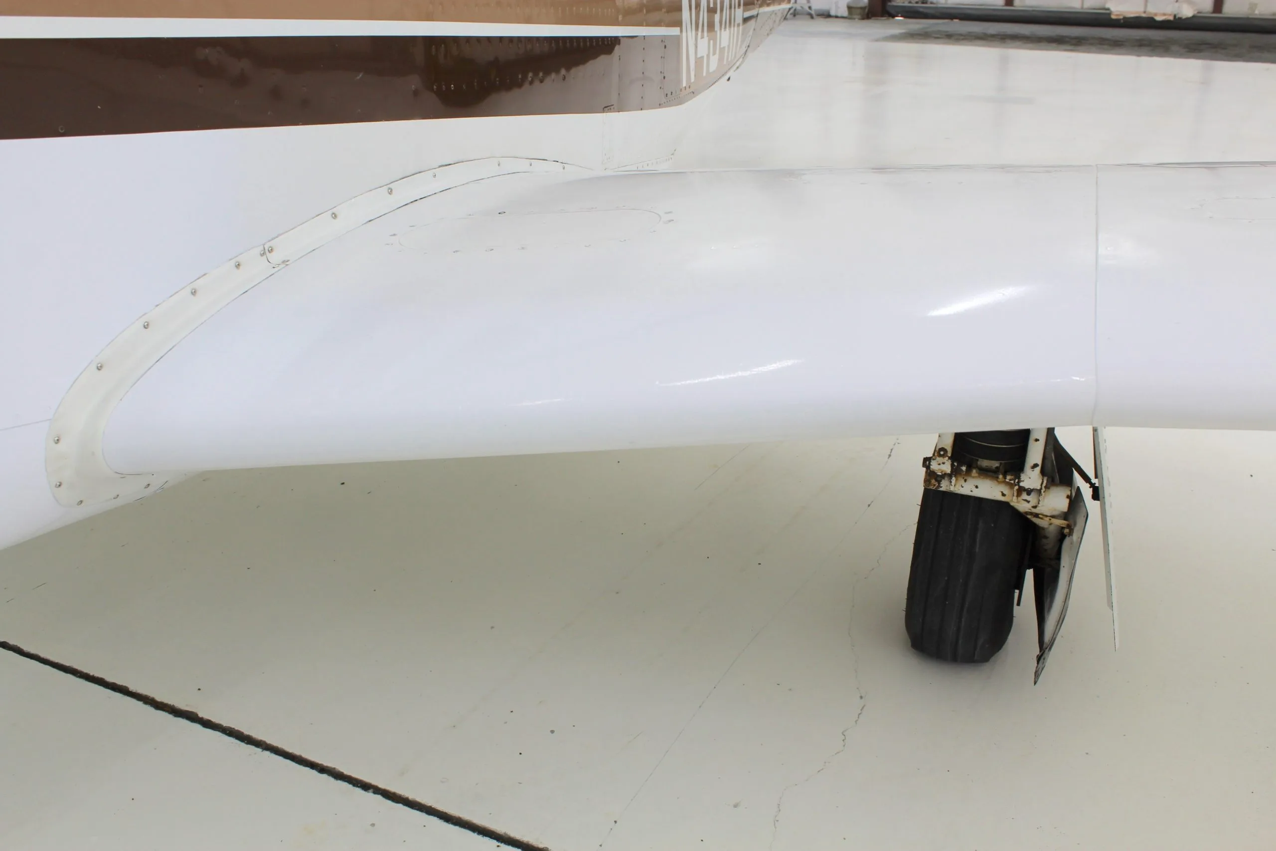 Close-up of the wing and landing gear of a Mooney M20J aircraft with registration N4341H.