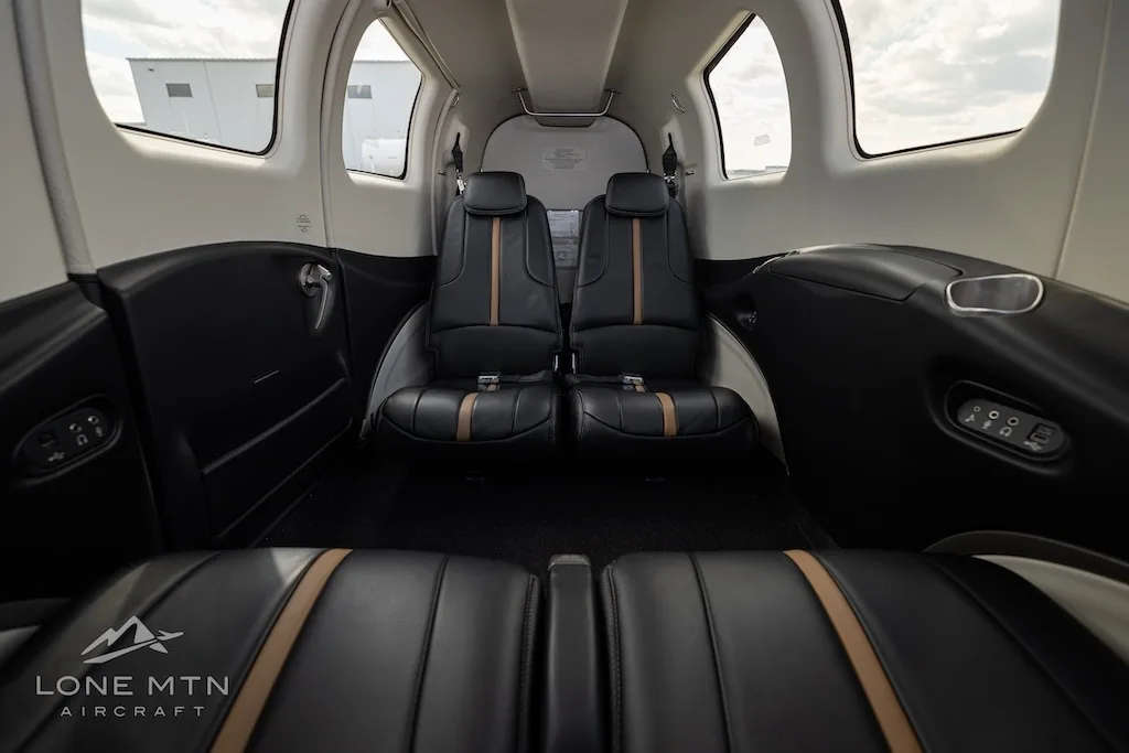 The interior cabin of the aircraft, showing black leather seats with tan accents.