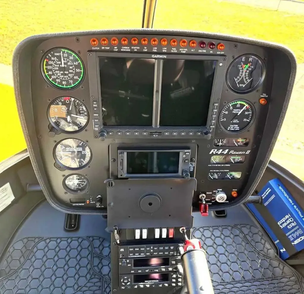 The instrument panel of a Robinson R44 Raven II helicopter, featuring a Garmin display and various gauges.