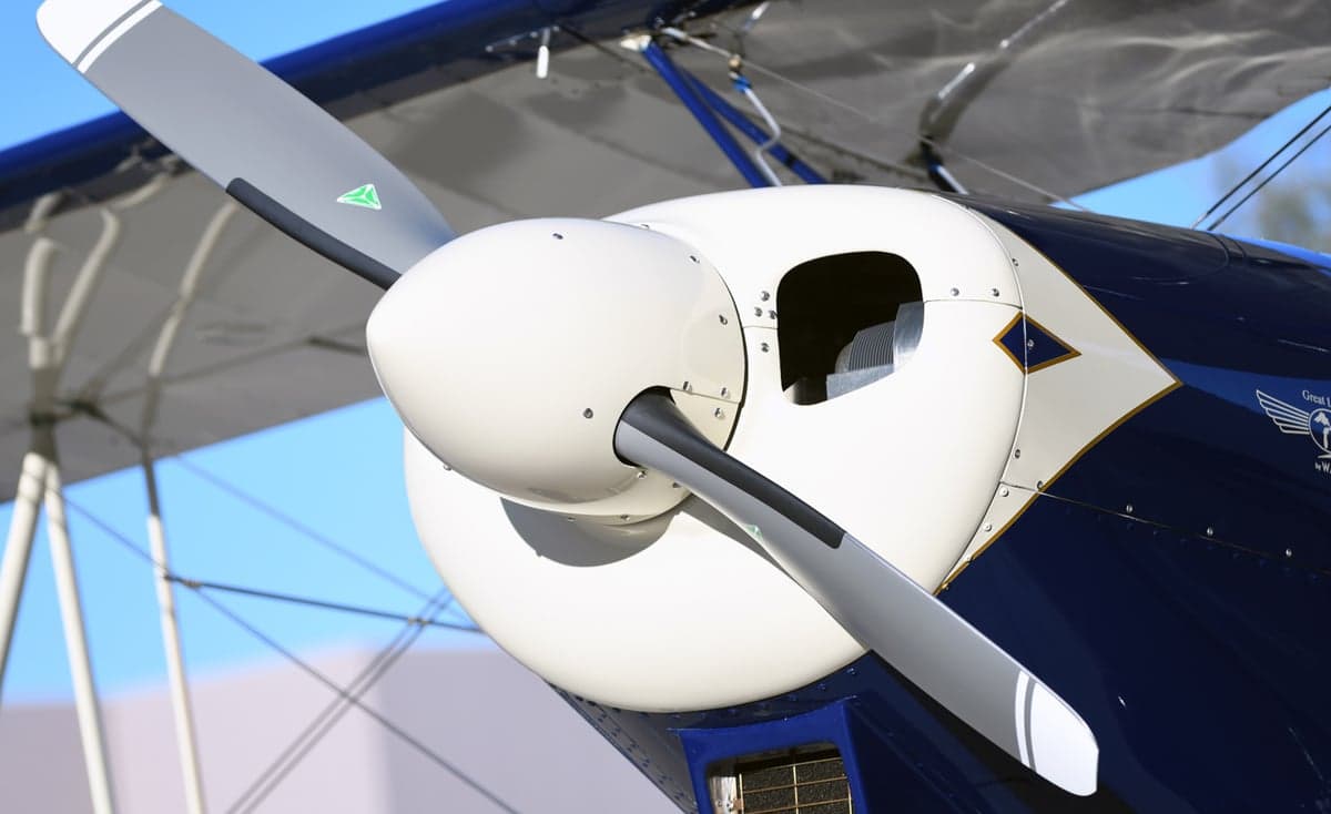Close-up of the propeller and nose of a blue and white biplane.