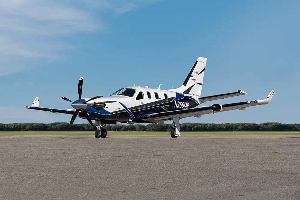 A TBM 960 aircraft with blue and white paint scheme, registration N960MR, parked on an airfield, viewed from the front-right.