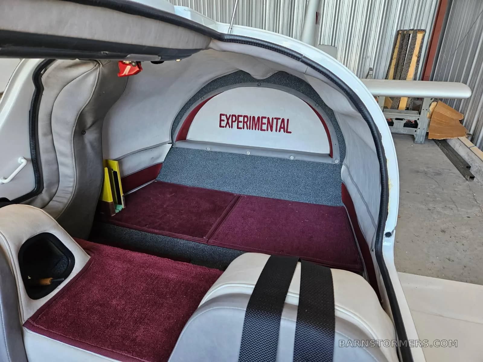 The rear interior cabin of a Europa aircraft with red carpet and an "EXPERIMENTAL" sign.
