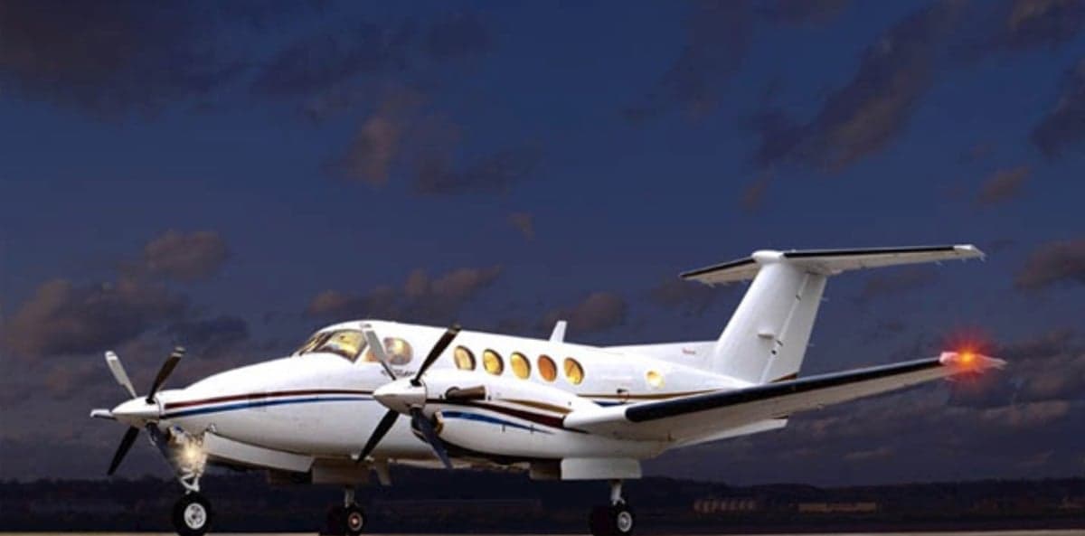 A King Air turboprop aircraft is parked on the tarmac at dusk.