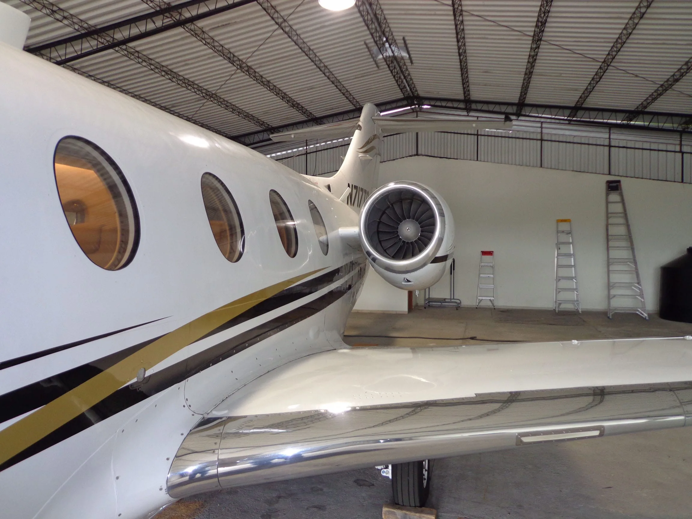 A close-up of the rear fuselage and engine of a white Beechjet 400A, showing the polished wing surface inside a hangar.