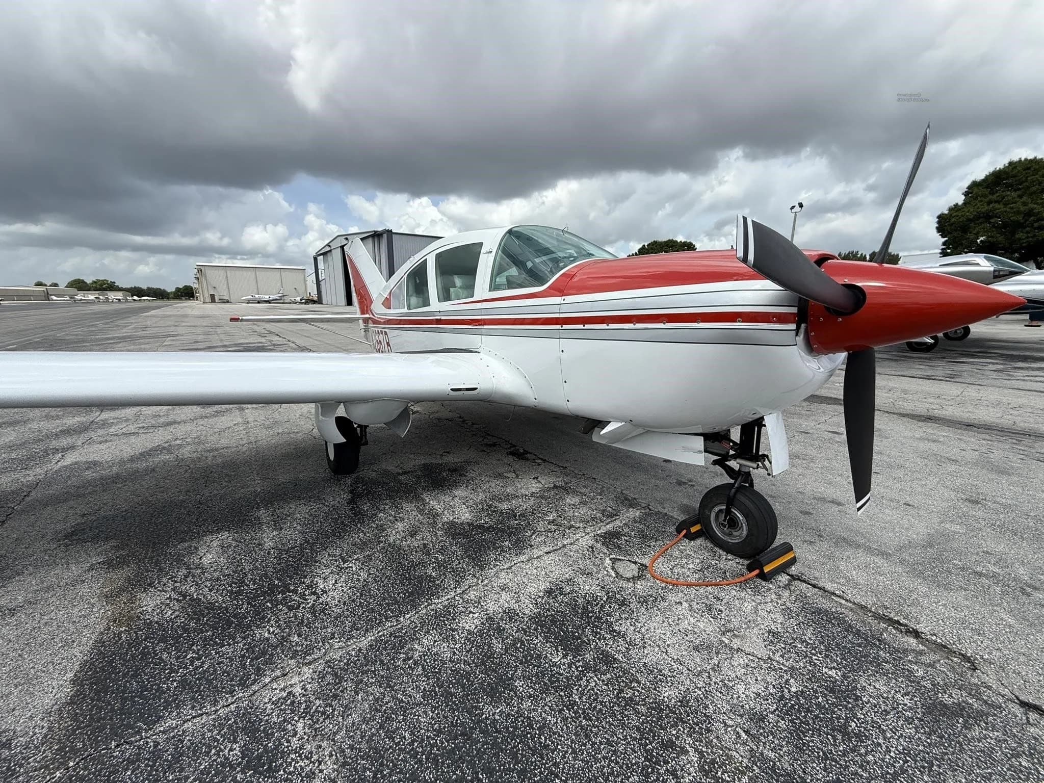 A low-angle front-right view of the white and red single-engine aircraft, N2667B, on the tarmac.