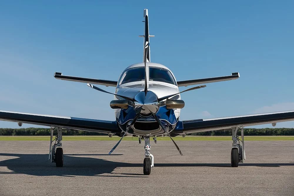 A head-on view of the TBM 960 aircraft with blue and white paint scheme, parked on an airfield.