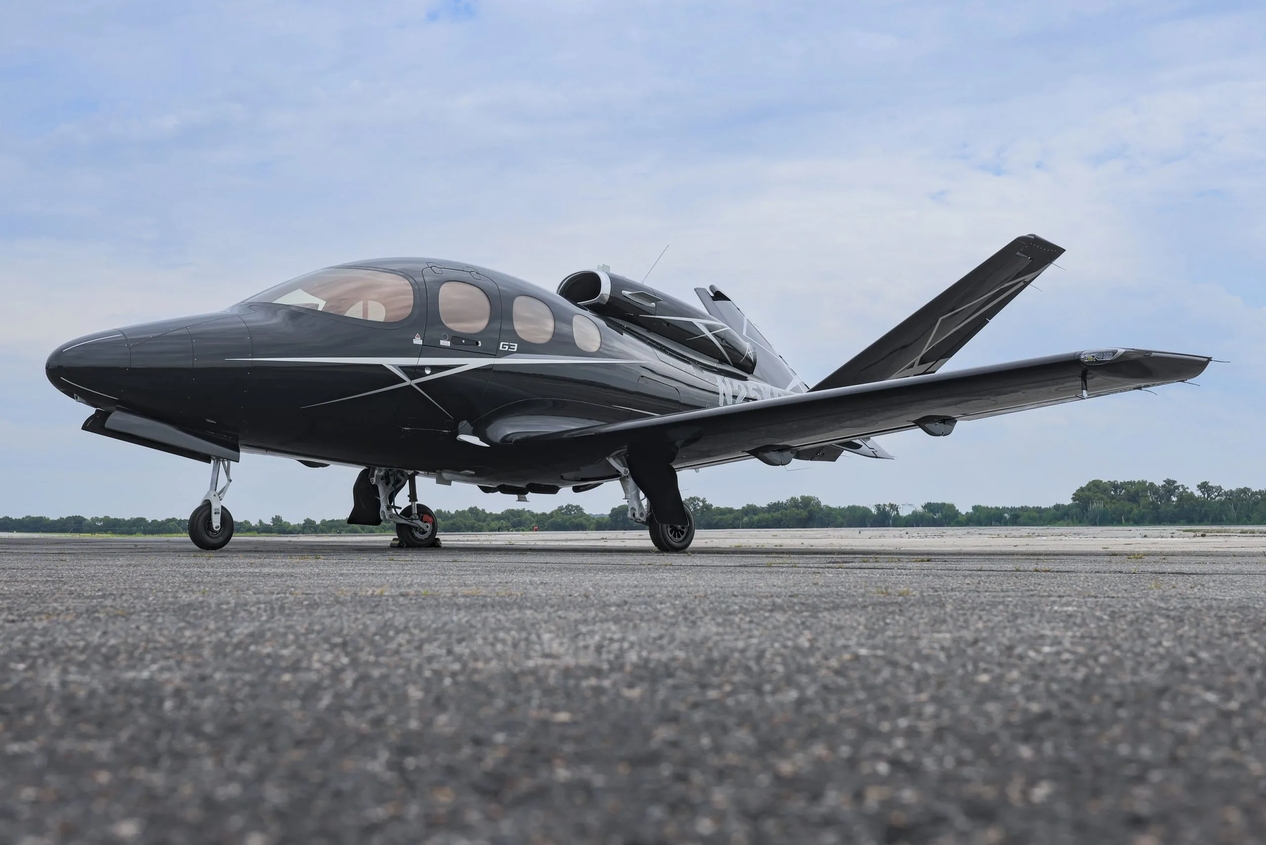 A low-angle view of a black Cirrus Vision Jet (N25KQ) parked on an airport tarmac.