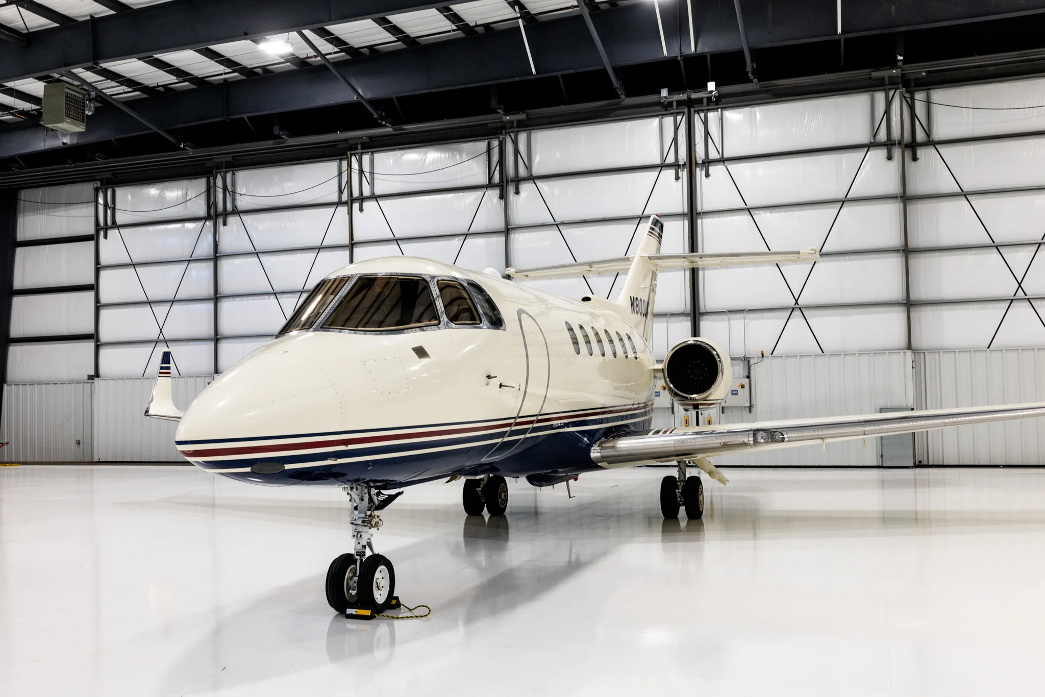 A front-quarter view of the N800UK business jet parked inside a brightly lit hangar.