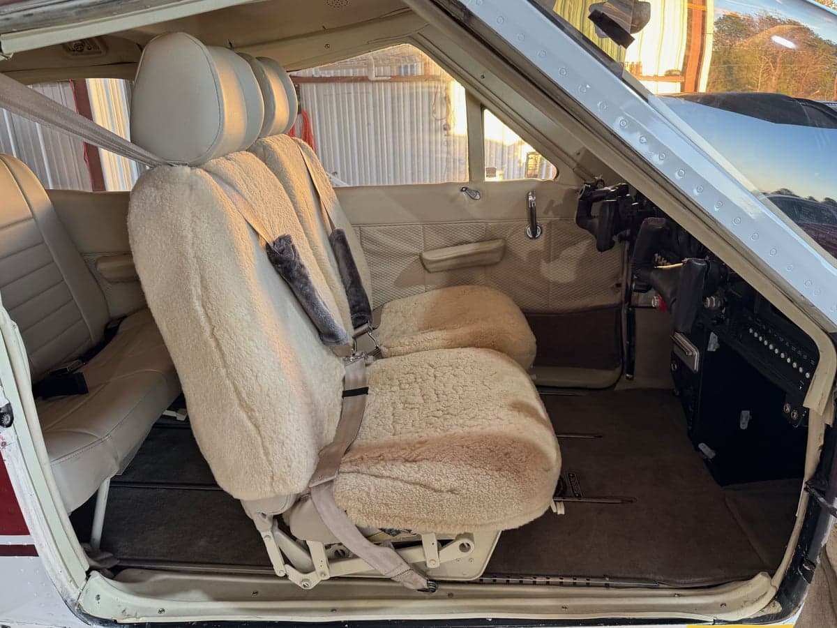 The interior of the aircraft features sheepskin seat covers and tan upholstery.