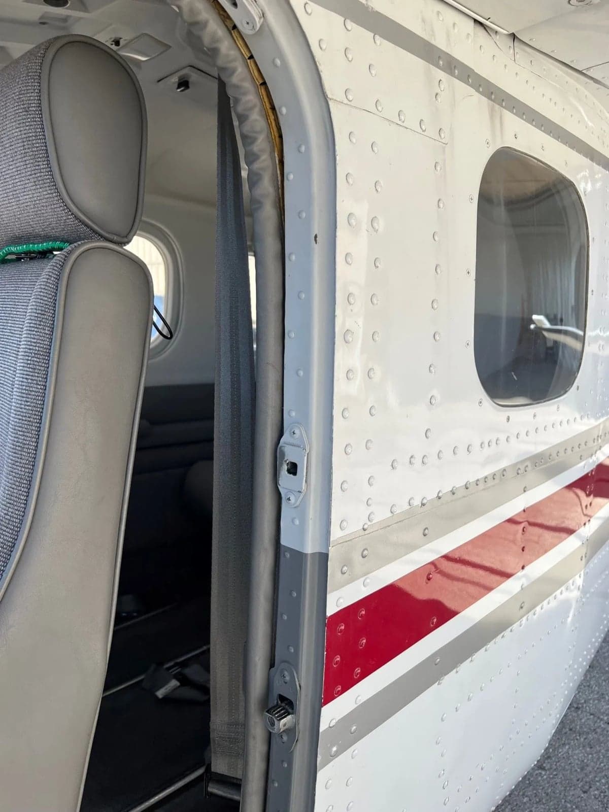 View of the open aircraft door and the grey fabric and leather interior seating.