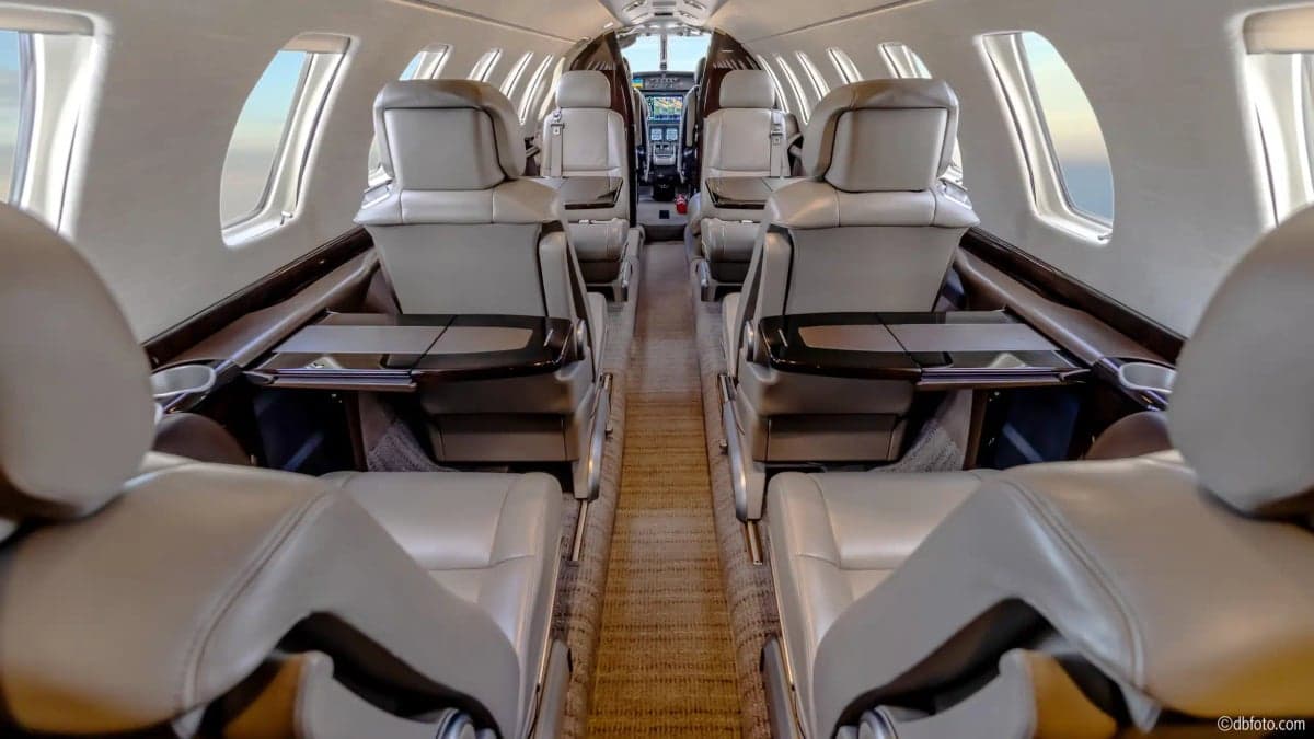 View of the aircraft's interior cabin with leather seats and fold-out tables.