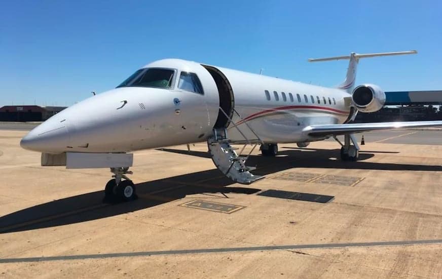 Embraer Legacy aircraft with open door and airstair on the tarmac.