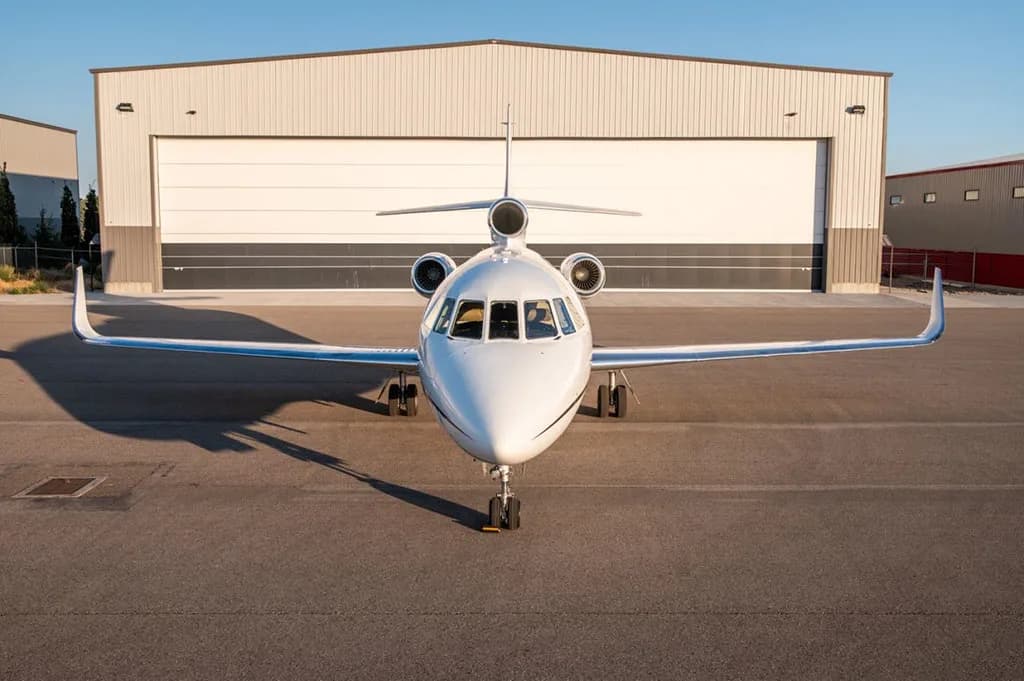 A front view of the Dassault Falcon 900EX business jet, registration N504PA, parked on the tarmac in front of a hangar.