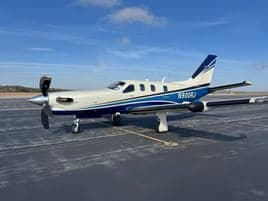 A TBM 930 aircraft with a blue and white paint scheme on the tarmac.